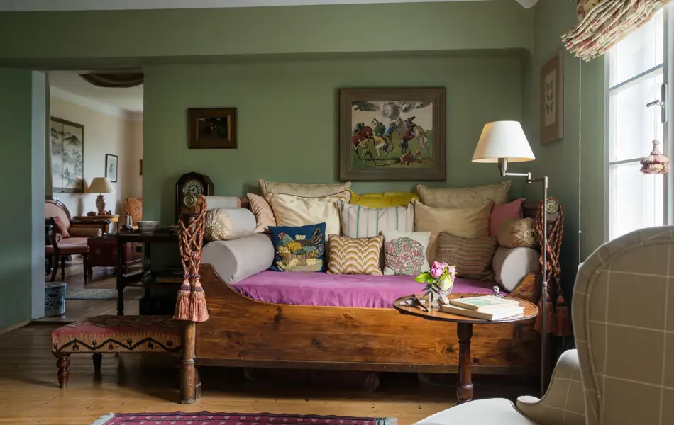 Assorted cushions on antique daybed in in sitting room with kelim upholstered ottoman