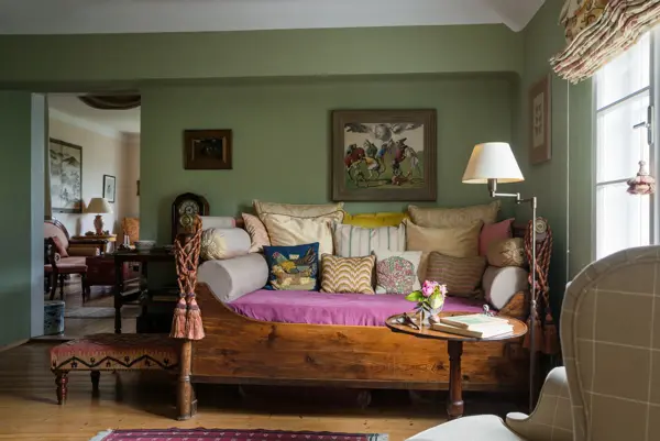 Assorted cushions on antique daybed in in sitting room with kelim upholstered ottoman