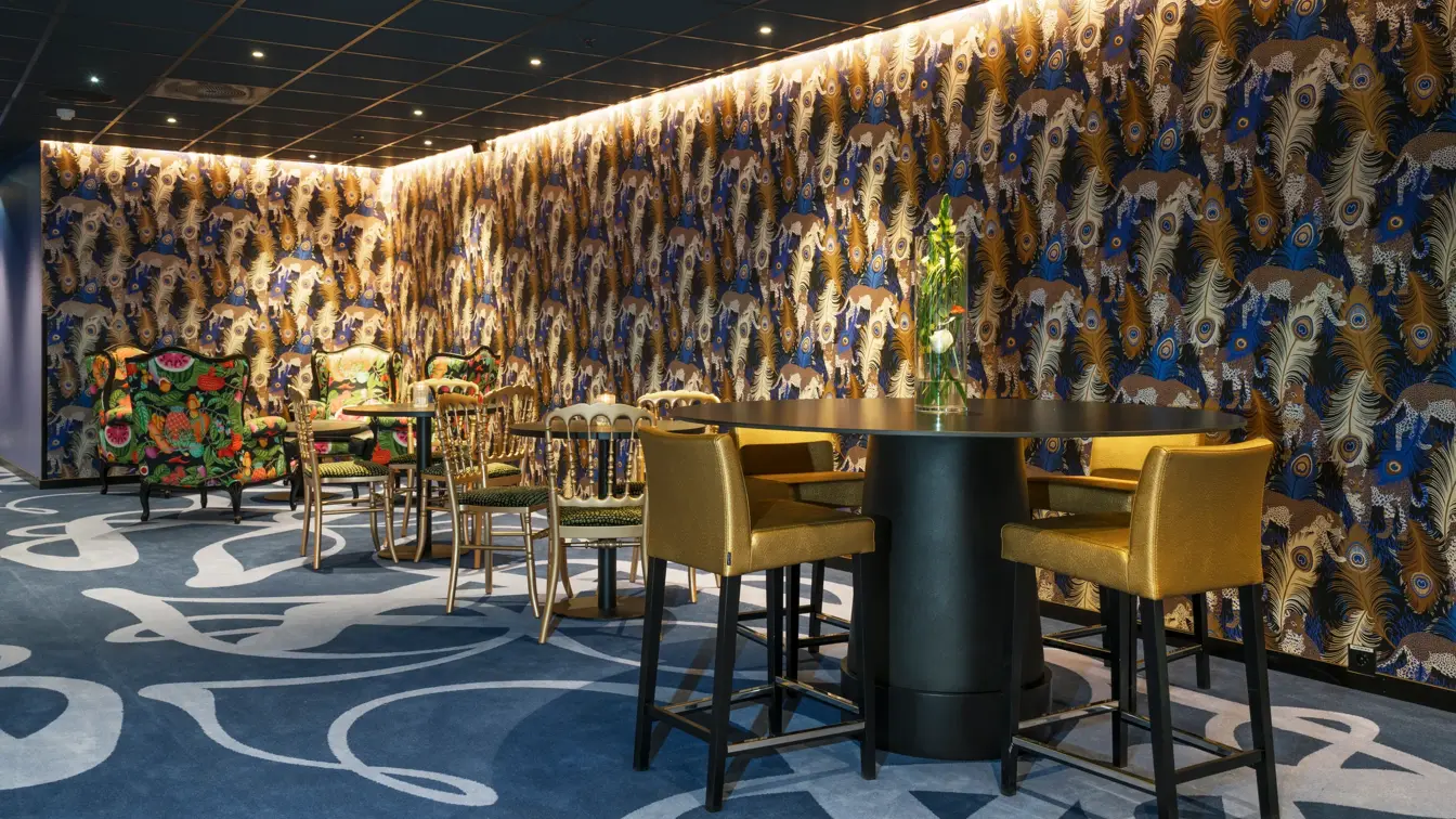 Teppe med mønster og påfugl-tapet, gullfarget barstoler og bord i lounge på Thon Hotel Terminus i Oslo sentrum nær Jernbanetorget