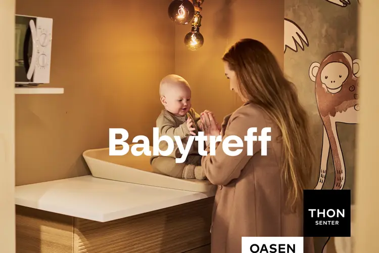 Bilde av en dame og en baby inne på et ammerom som leker mens babyen sitter på stellebordet. 