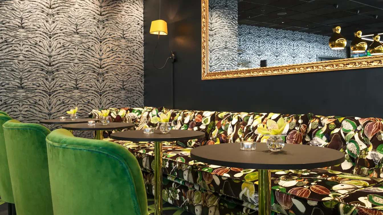 Lounge med mønstret sofa, lenestoler i grønne farger og stort speil over sofa på Thon Hotel Stavanger midt i Stavanger sentrum