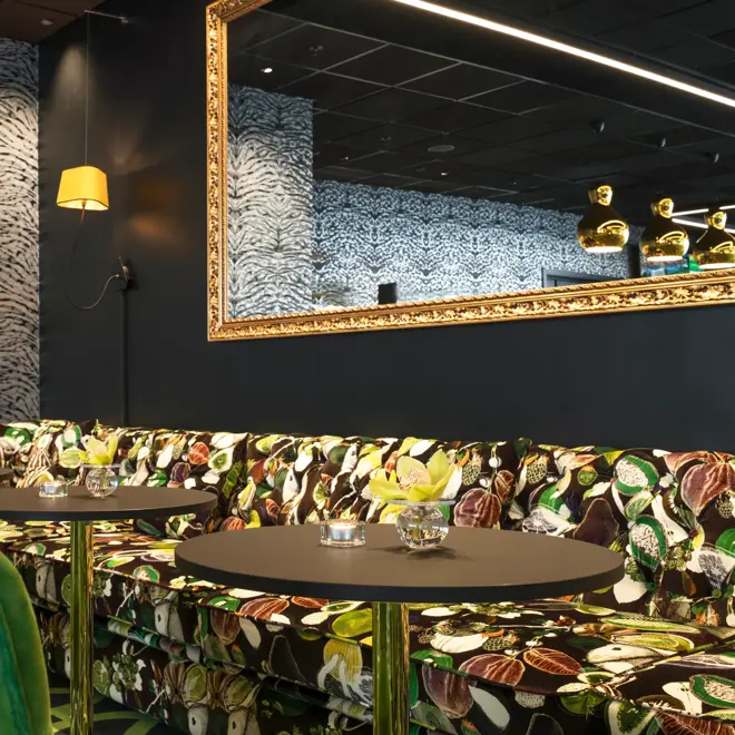 Lounge med mønstret sofa, lenestoler i grønne farger og stort speil over sofa på Thon Hotel Stavanger midt i Stavanger sentrum