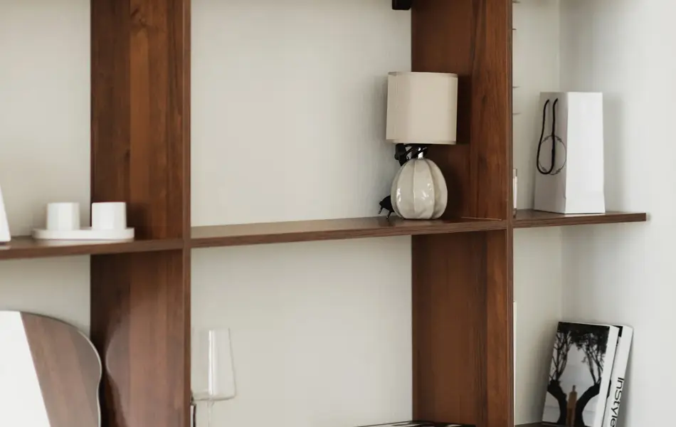 Nærbilde av hylle i mørkt tre med bølgespeil og diverse bøker og  pyntegjenstander 