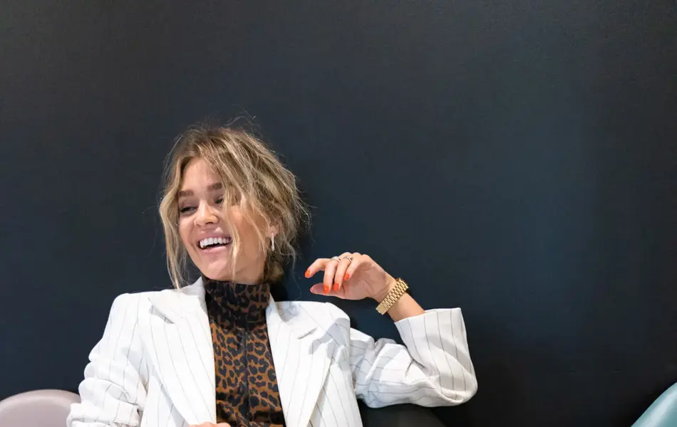 Ung kvinne i hvit dress smiler og ler