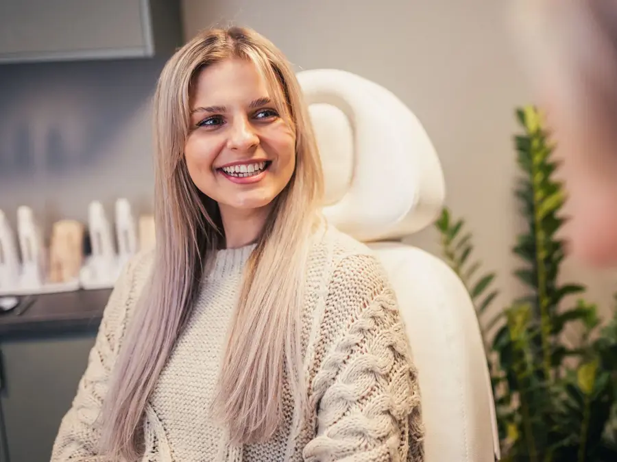 Jente sitter i en behandlingsstol og smiler