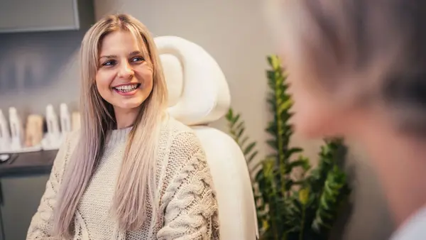 Jente sitter i en behandlingsstol og smiler