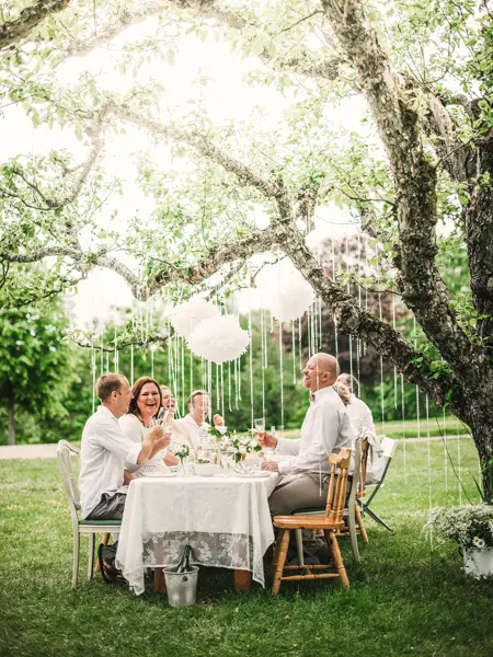 Gruppe ved bordet med dekorasjoner hengende fra trærne over