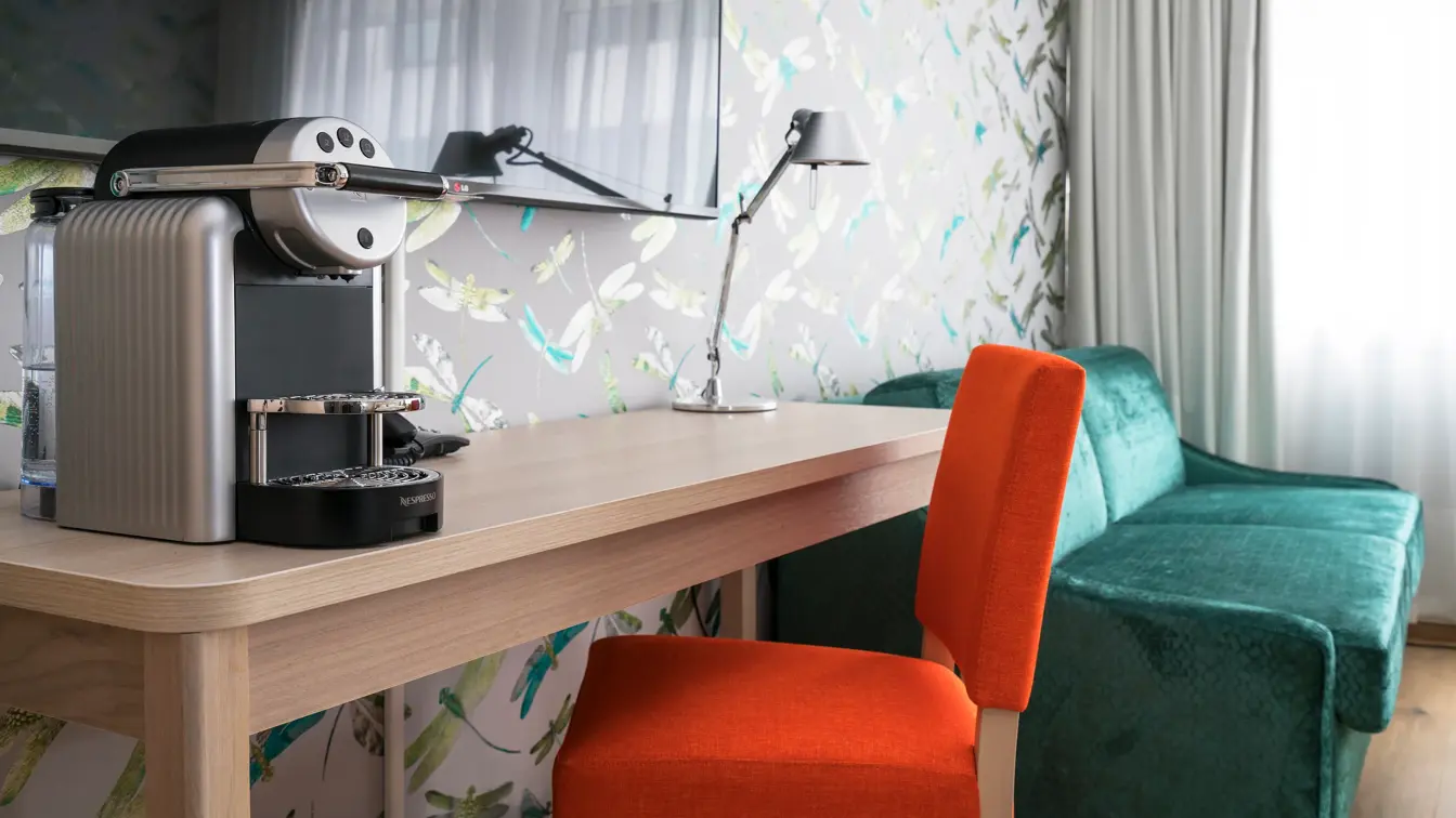 Arbeidsplass med kaffemaskin, stol og sofa i bakgrunnen på businessrom på Thon Hotel Polar