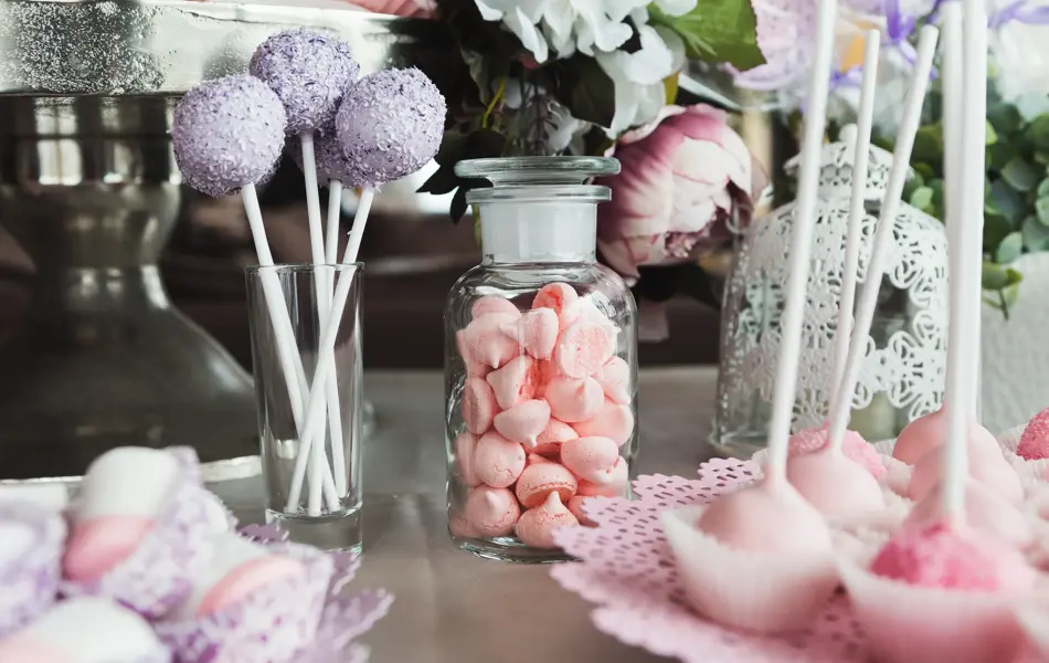 Pink candy bar for holiday celebration. Sweet buffet for birthday party or wedding. Desserts assortment against wooden background, catering concept