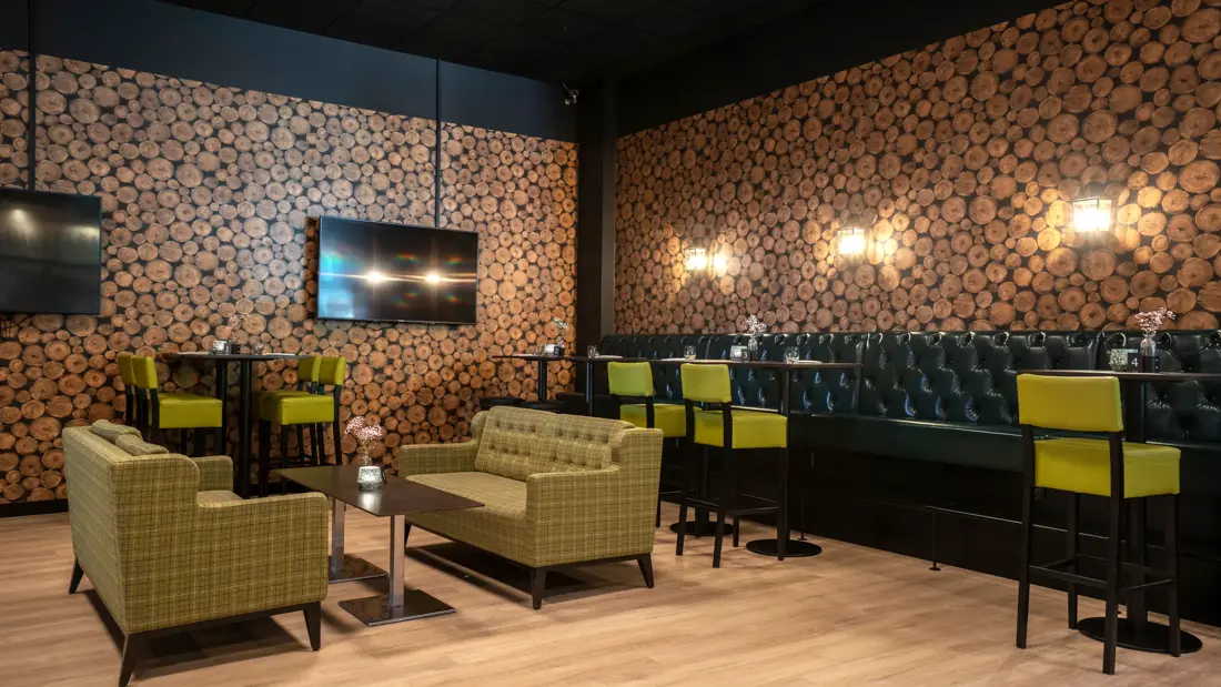 Svart spisesofa, salongbord, parkettgulv, gule barstoler, sittegruppe med sofa, tapetvegg, TV