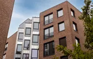 Moderne leilighetsbygg med teglfasade og store vindusflater sett fra indre gårdsrom.
