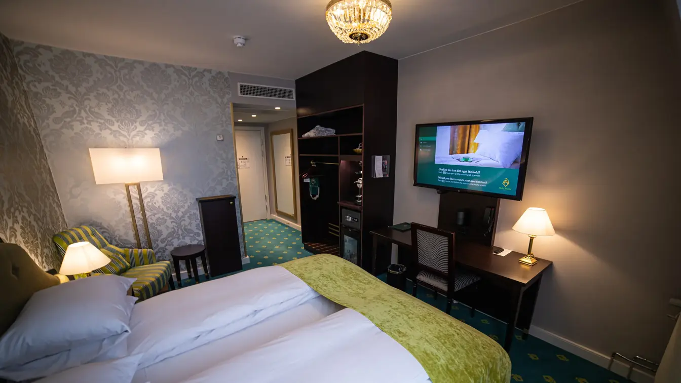 Dobbeltseng, lenestol, teppegulv og lysekrone, tv på vegg og skrivebord med stol 