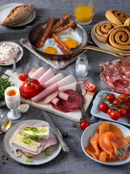 Bord dekket med pålegg - skinke, ost, laks, egg, tomater og boller