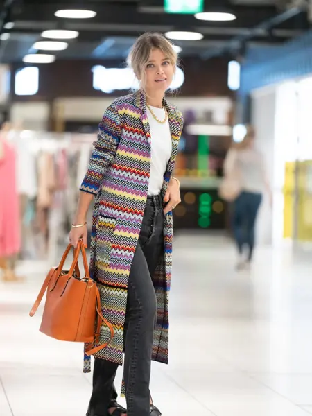Ung kvinne som poserer i trendy antrekk på kjøpesenter