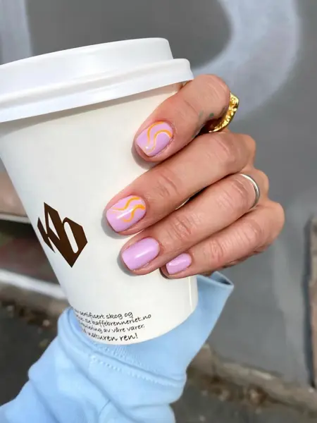 Dame som holder en take away kopp og har nye lakkerte negler