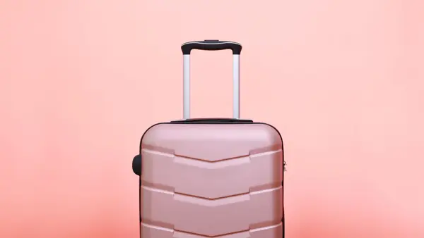 Rosa koffert foran rosa bakgrunn