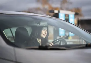 En kvinne som sitter i bilen og ser ut av vinduet.