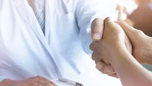 Doctor holding patient's hand, and reassuring his male patient helping hand concept.