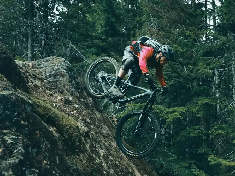 Mann med orange jagge kjører terrengsykkel nedover et bratt fjell