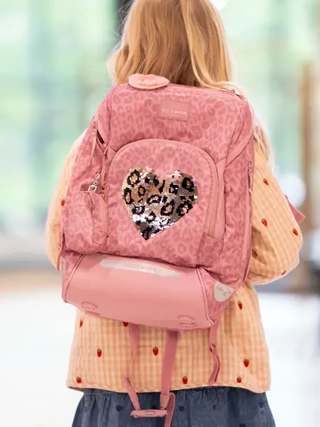 Jente med ryggen mot kamera med ytterjakke og rosa sekk på ryggen