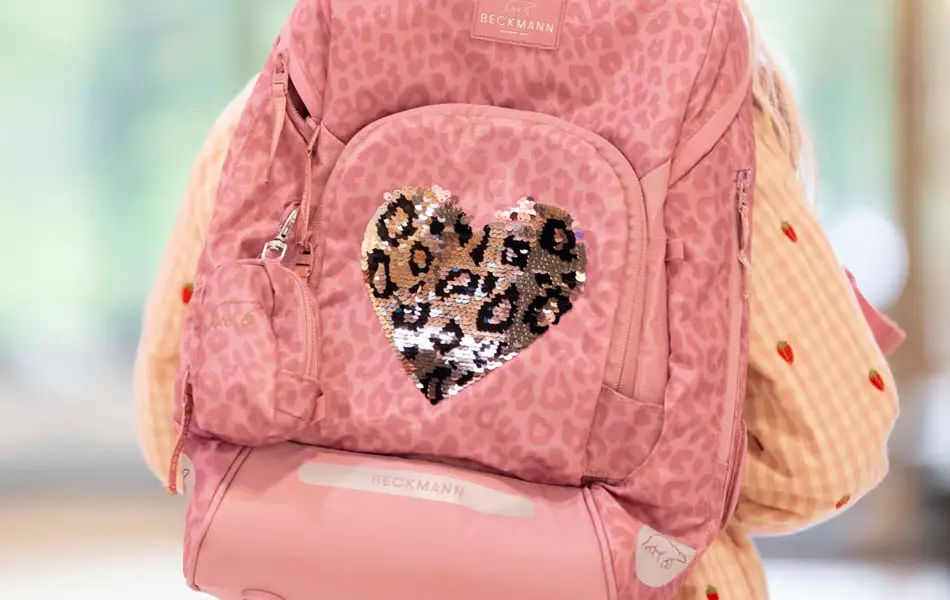 Jente med ryggen mot kamera med ytterjakke og rosa sekk på ryggen