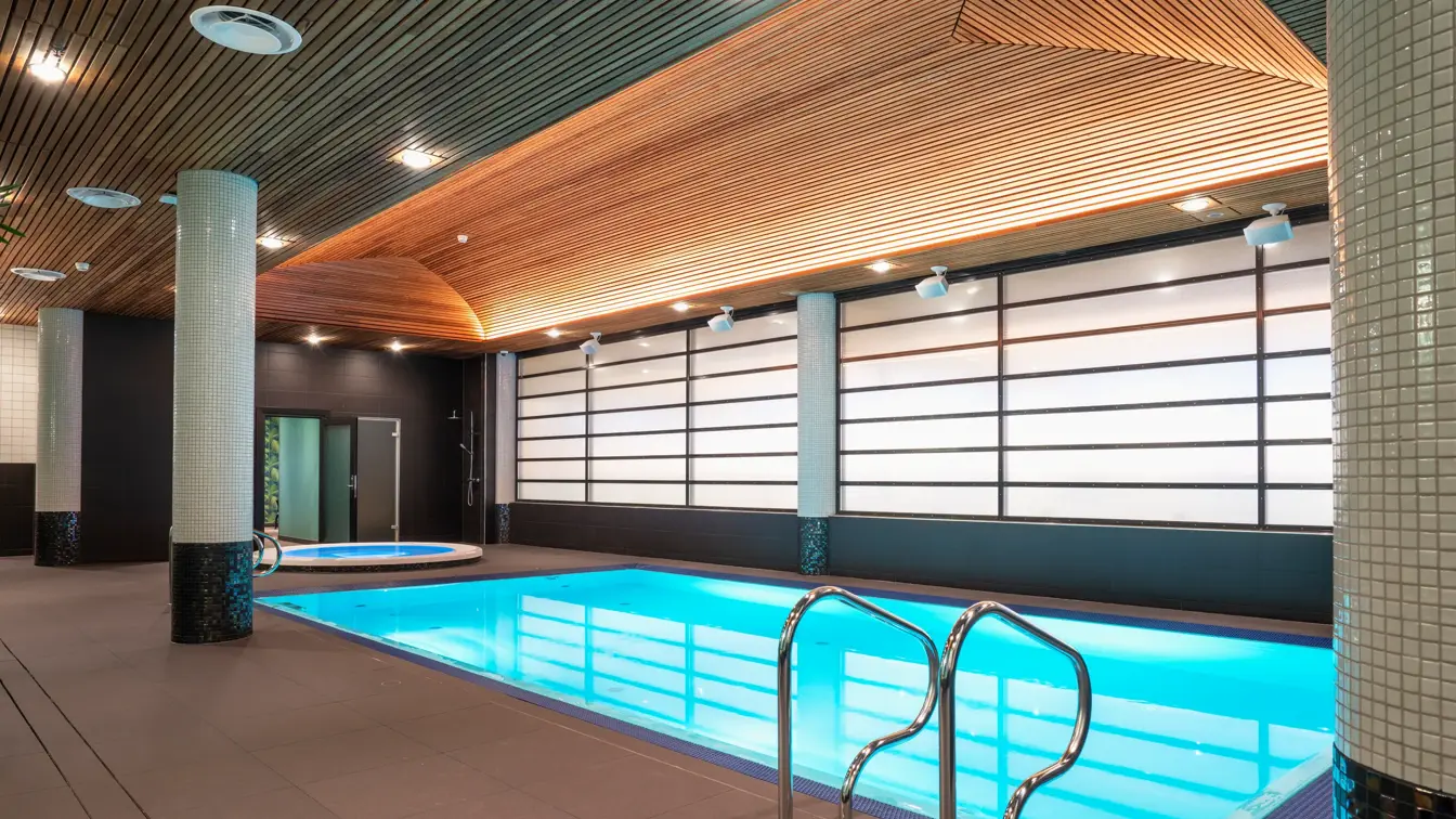 Trapp ned til badebasseng og rundt boblebad i bakgrunnen med dempede lys på Thon Hotel Arena i Lillestrøm