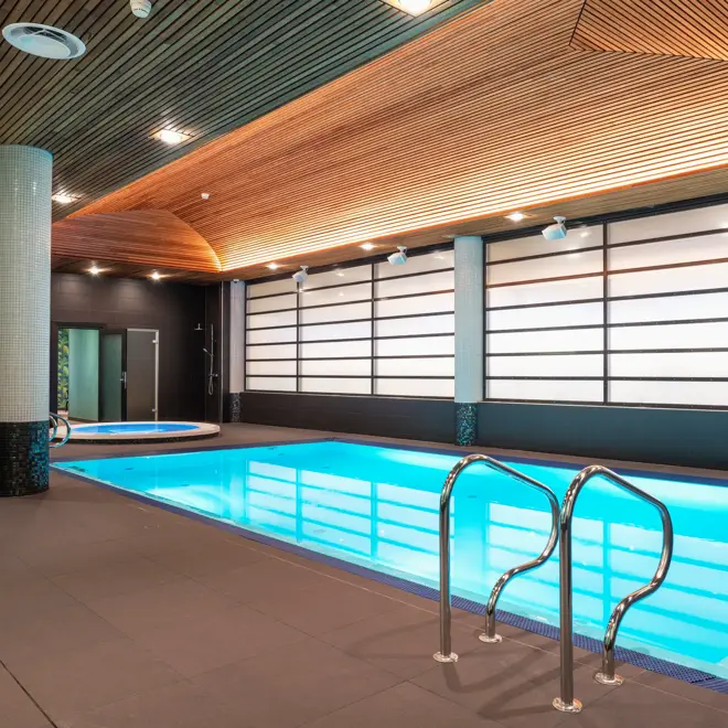 Trapp ned til badebasseng og rundt boblebad i bakgrunnen med dempede lys på Thon Hotel Arena i Lillestrøm