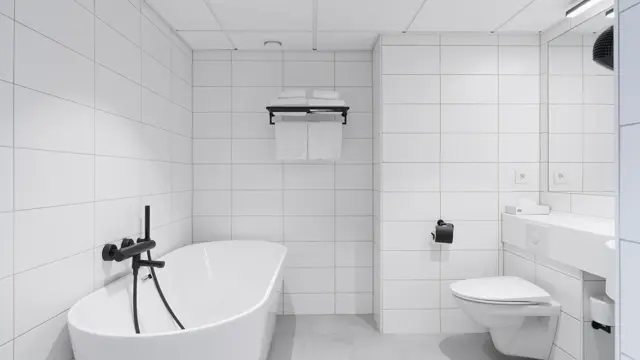 Flislagt bad med frittstående badekar, servant og toalett. 
