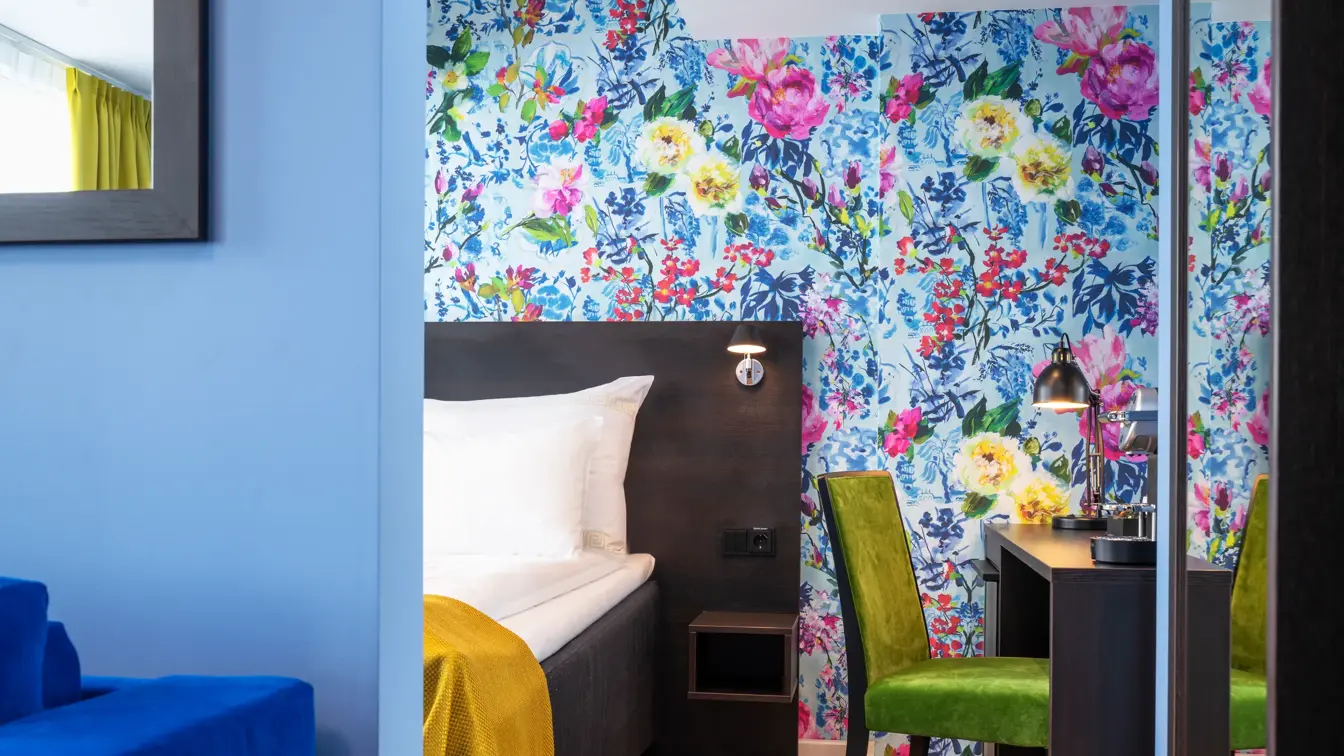 Seng, blomstrete tapet, skrivebord og grønn stol i business rom på Thon Hotel Moldefjord
