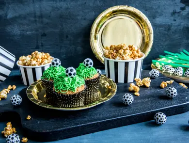 Bord med fotballcupcakes på gulltallerkener og popcorn i skåler 