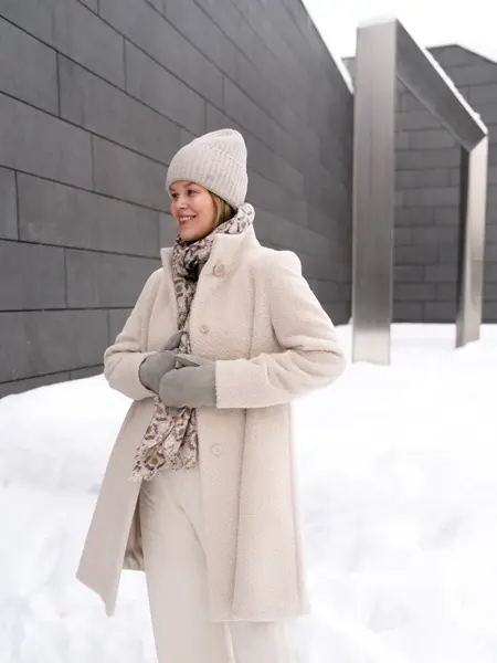 Dame med hvit lue, skjerf, hvit kåpe og bukse og grå votter