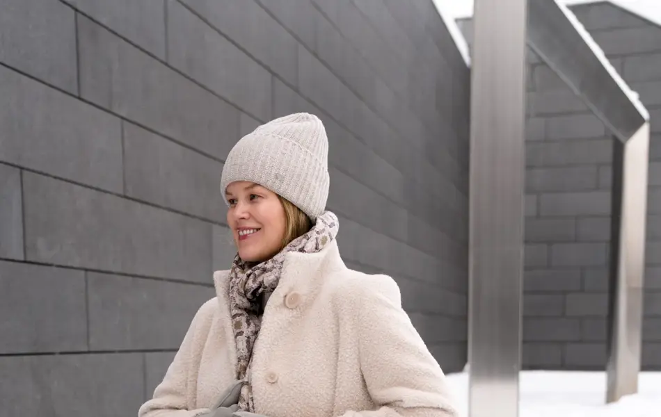 Dame med hvit lue, skjerf, hvit kåpe og bukse og grå votter