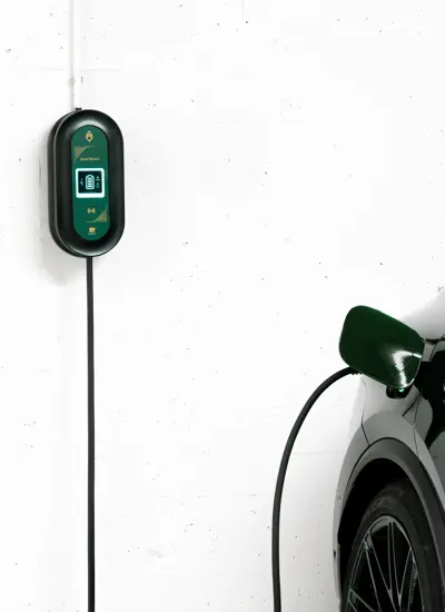 Del av en mørk bil står i en garasje med en ladekabel bak på en hvit vegg.