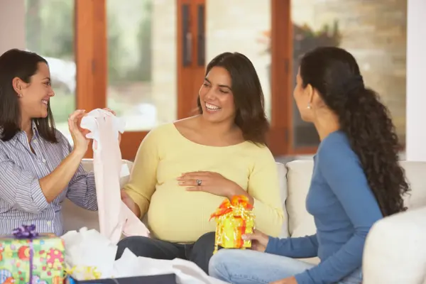 damer som sitter rundt gravid mor i casual klær med gaver