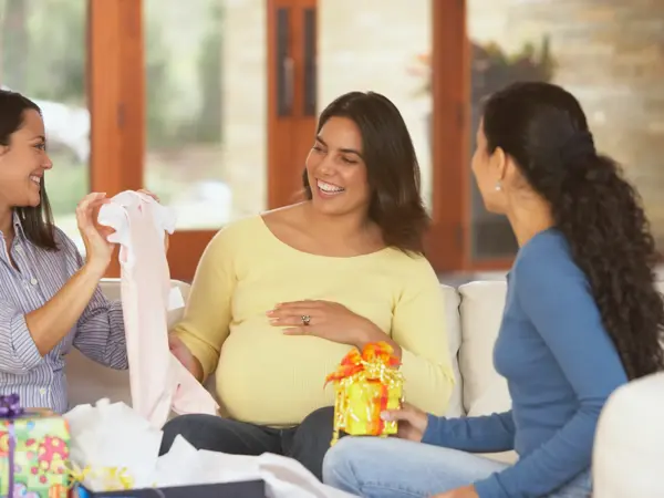 damer som sitter rundt gravid mor i casual klær med gaver