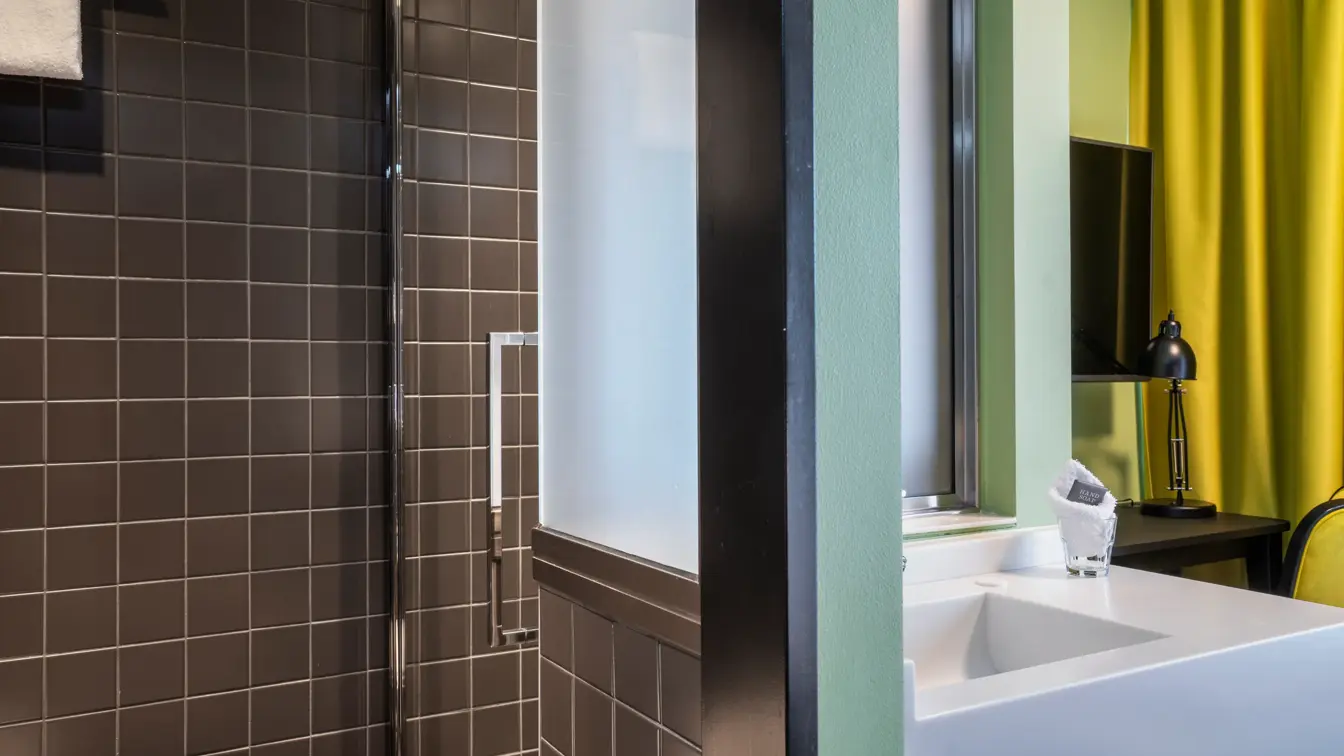 Svarte veggfliser, vask, dusj. 