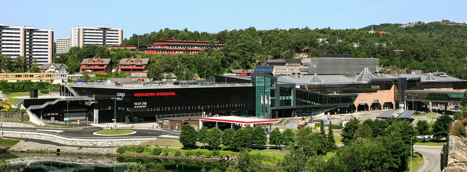 Fasadebilde av Vestkanten Storsenter fra avstand viser rundkjøring ved senteret