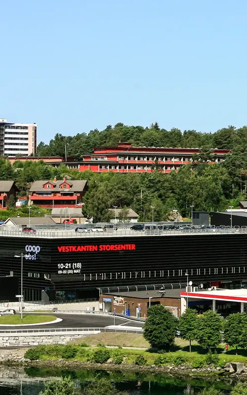 Fasadebilde av Vestkanten Storsenter fra avstand viser rundkjøring ved senteret