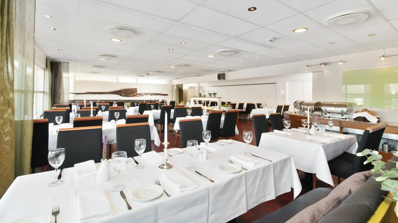 Restaurant med lange bord med hvite duker og sorte stoler i restauranten til Thon Hotel Sandnes