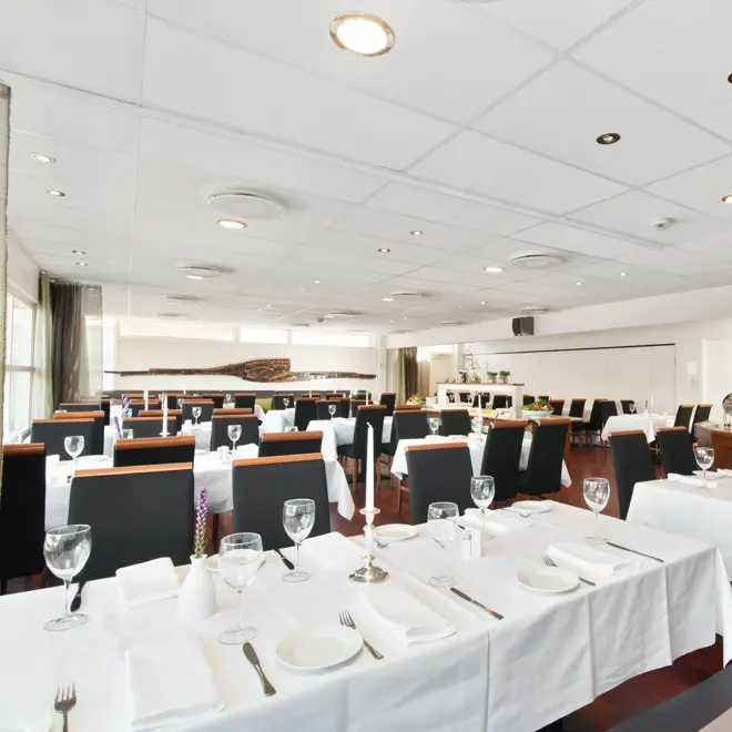 Restaurant med lange bord med hvite duker og sorte stoler i restauranten til Thon Hotel Sandnes