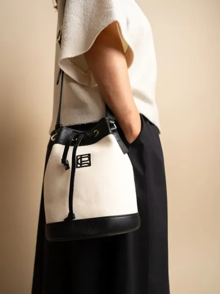 Dame med hvit topp, sort og hvit veske over skulderen og sort skjørt.