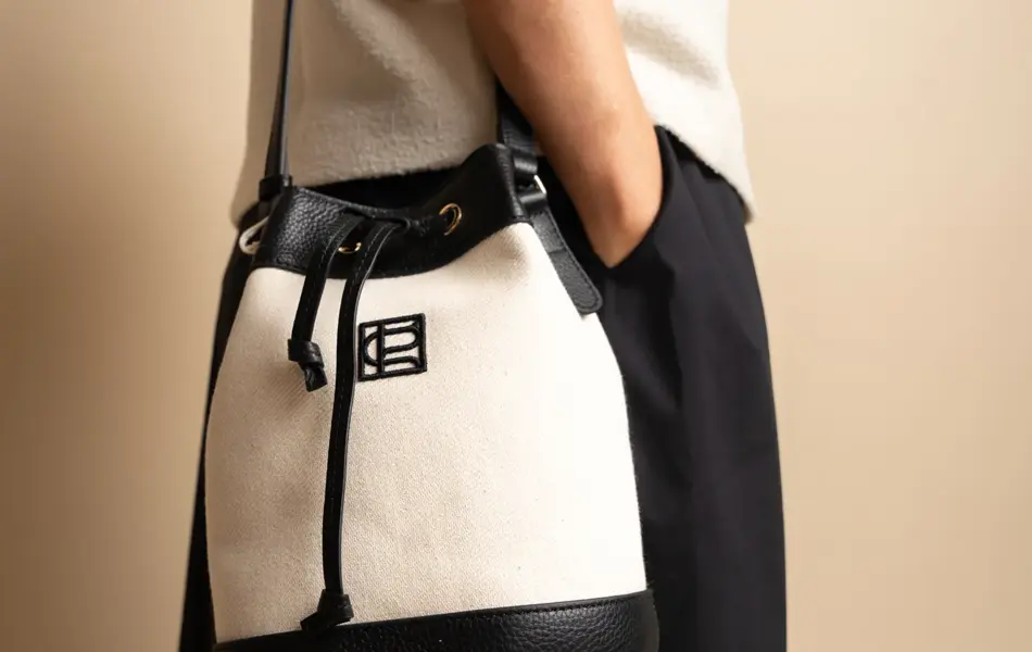 Dame med hvit topp, sort og hvit veske over skulderen og sort skjørt.