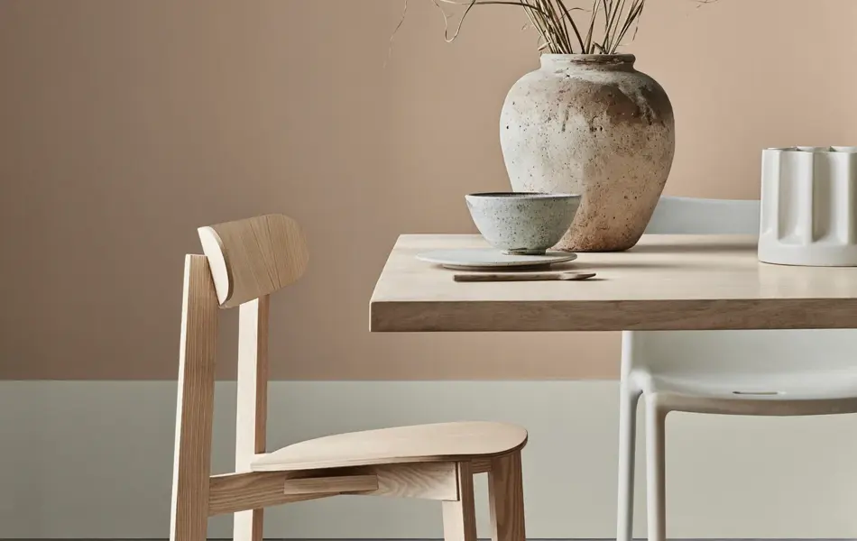 Utsnitt av trestol i såpevasket eik som står foran et bord i samme treverk