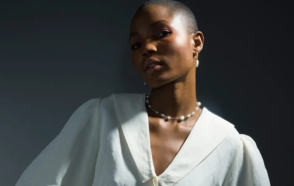 Dame med hvit bluse med innsvinget midje poserer for kamera