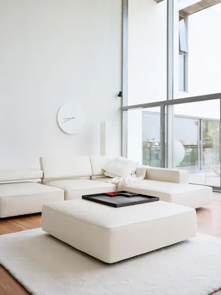 Helt hvit stue med hvit ottoman med trebrett som stuebord