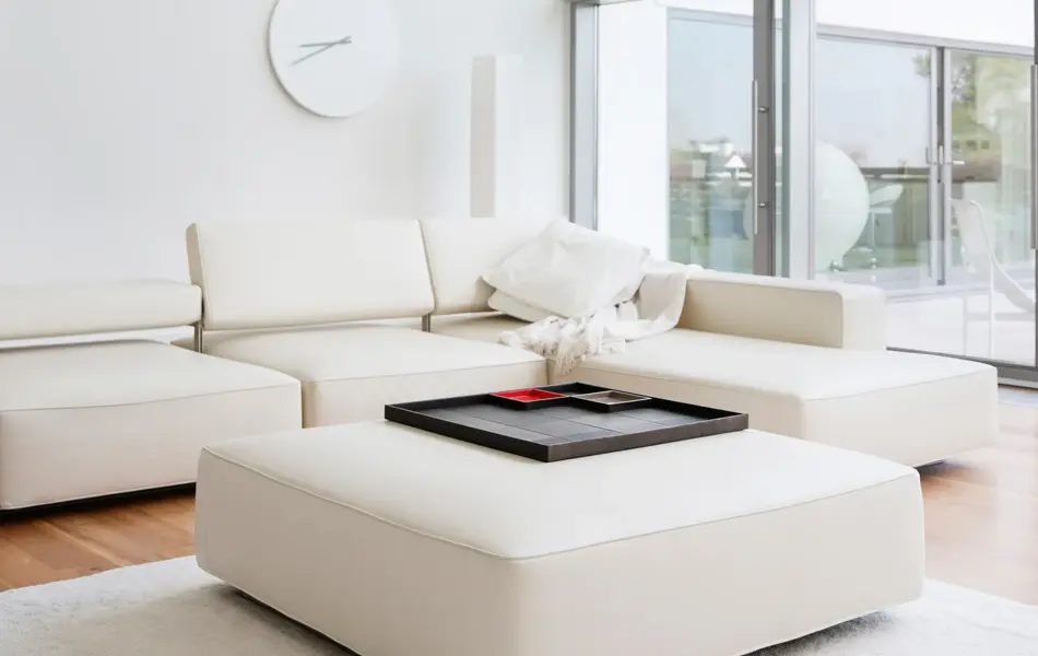 Helt hvit stue med hvit ottoman med trebrett som stuebord