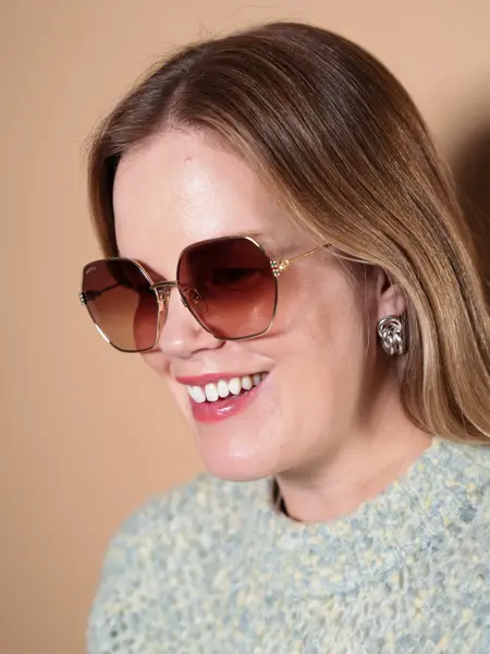 Dame med Gucci solbriller med gull-innfatning og store glass.