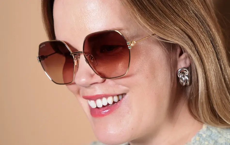 Dame med Gucci solbriller med gull-innfatning og store glass.
