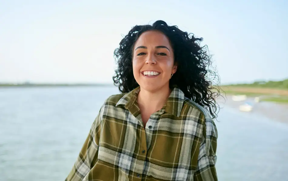 Dame med grønn flanellskjorte smiler i kamera 