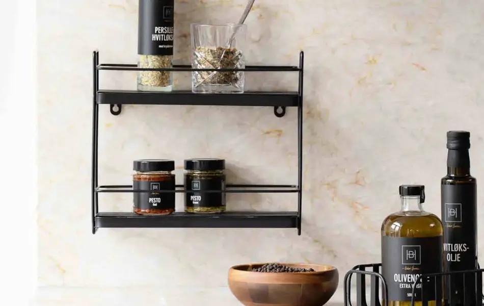 Kjøkkenbenk med oljer, boller og en hylle på veggen.